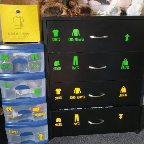 Image shows a set of drawers with clothing labels on it - tops, pants, long sleeve, singlets, undies/underwear etc